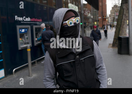 Mann trägt eine schwarze Maske über seinem Gesicht und Sonnenbrille mit Cartoon-Augen gedruckt auf den Linsen, verbirgt seine Identität in London, England, Vereinigtes Königreich. Stockfoto