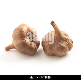 zwei schwarze oder braune Knoblauch auf einem weißen Hintergrund mit einem weichen Schatten Stockfoto