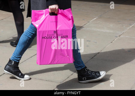 Shopper in der Londoner Oxford Street trägt eine rosa House of Fraser Plastiktüte. Stockfoto