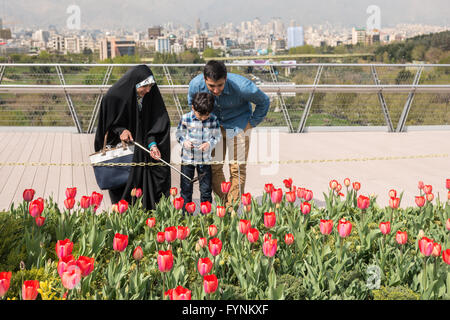 Mutter im Tschador, wobei ein Selbstporträt von ihrer Familie auf der Tabiat-Brücke in Teheran, Iran. Stockfoto