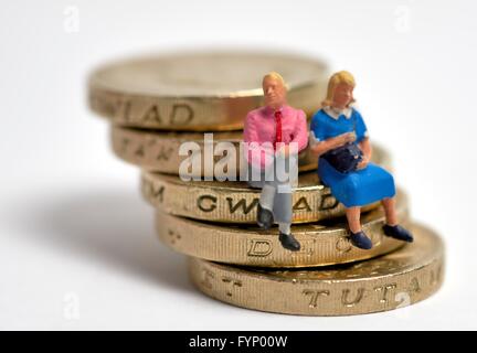 Miniatur verheiratet paar sitzt auf einem Stapel von 1 Pfund-Münzen Stockfoto