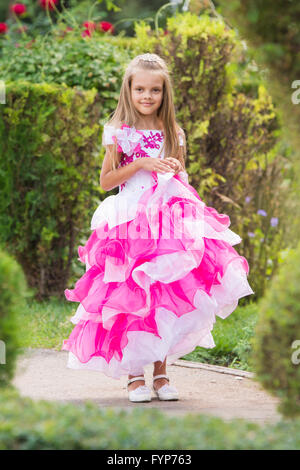 Mädchen im Abendkleid in einem üppig grünen Garten Stockfoto