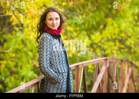 Brustbild eines schönen jungen Mädchens auf der Brücke vor dem Hintergrund der Herbst Laub gelb Stockfoto