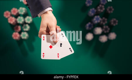 Elegante männlichen Pokerspieler hält zwei Asse mit Stapeln von Chips auf Hintergrund und grünen Tisch, Ansicht von oben Stockfoto