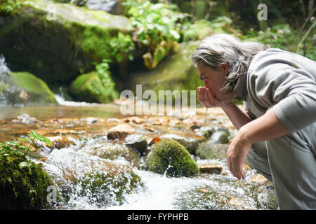 frisches Trinkwasser vom Frühling Mann Stockfoto