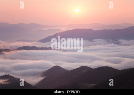 Sonnenaufgang über dem bewölkten Bergrücken Stockfoto
