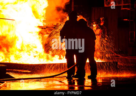 Feuerwehrleute mit Wasserschlauch auf Feuersbrunst Stockfoto