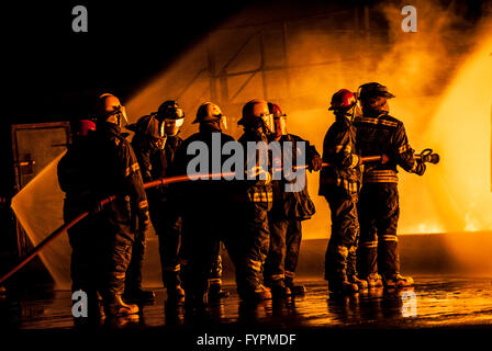 Gruppe der Feuerwehrleute kämpfen ein brennendes Feuer Stockfoto