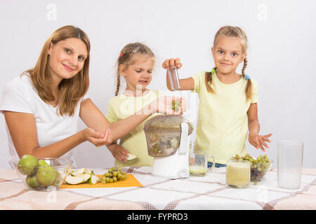 Sie und ihre beiden Töchter gepresster Saft in einen Entsafter Stockfoto