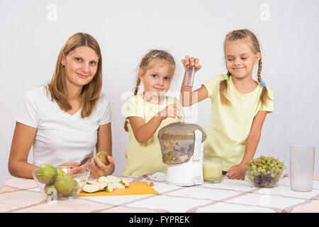 Glückliche Familie bereitet frisch gepressten Saft in einen Entsafter Stockfoto