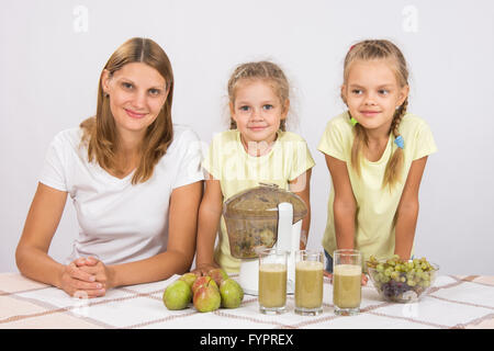 Mutter und zwei Töchter, drei Gläser Saft Saftpresse Kochen Stockfoto