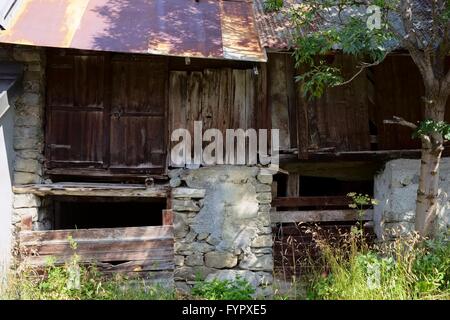 Detaillierten Fassade Ansicht einer maroden verfallenen Scheune aus Steinen, Holz und rostigen Metall Pfanne Teller Dach Stockfoto