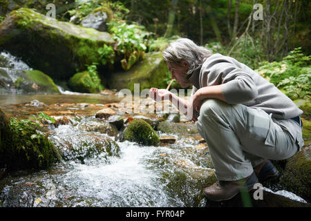 frisches Trinkwasser vom Frühling Mann Stockfoto