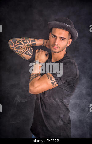 Schön und stilvoll junger Mann mit schwarzer Melone und T-shirt. Coolen Tattoos an Armen Stockfoto