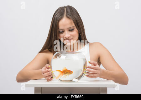 Hübsches Mädchen untersucht einen Goldfisch im aquarium Stockfoto