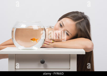 Schöne Mädchen träumt und sieht einen Goldfisch im aquarium Stockfoto
