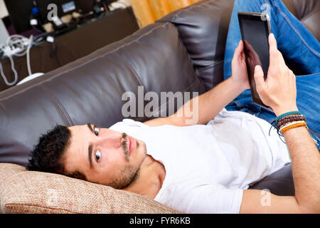Junge Männchen mit Tablet auf einer couch Stockfoto