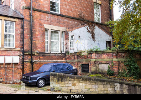 Ein blauer VW Golf MK2 Cabrio Limousine Auto mit einer Abdeckung über es, neben einem alten heruntergekommenen Haus in Durham City, County Durham, England, UK geparkt Stockfoto