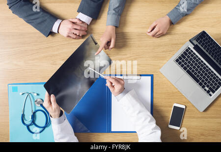 Radiologe arbeitet an seinem Schreibtisch Überprüfung des Patienten Röntgen und deutete mit einem Stift, Top anzeigen nicht erkennbare Personen Stockfoto