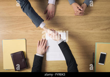 Successful Business Büro Schreibtisch Handshake nach Unterzeichnung eines Abkommens, übergibt Draufsicht, unkenntlich Menschen Stockfoto