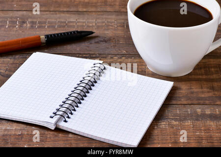 eine leere Arbeitsmappe, einen Stift und eine Tasse Kaffee auf einem rustikalen Holztisch Stockfoto