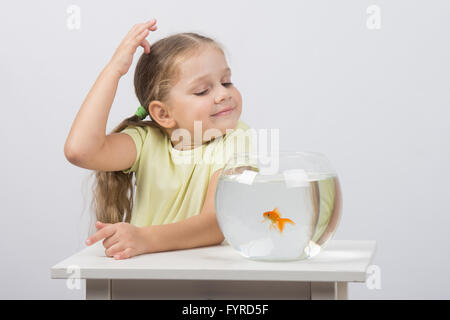 Vierjährige Mädchen machen einen Wunsch und genießen Sie einen Goldfisch im aquarium Stockfoto