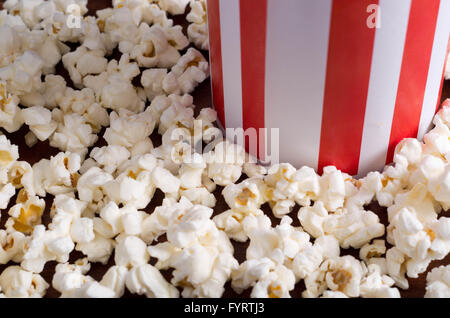Closeup rot weiß gestreift Container-Box stehend mit Popcorn herumliegen, niedrigen Winkel, grauen Hintergrund Stockfoto