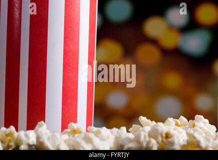 Closeup rot weiß gestreift Container Box stehend mit Popcorn herumliegen, niedrigen Winkel, auffällige lebendige Lichter Hintergrund Stockfoto