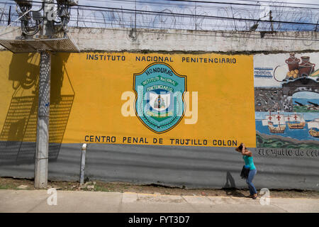 Ein Mann geht durch das gelbe gemalten Wandbild Zeichen außerhalb des Gefängnisses In Trujillo Honduras Stockfoto