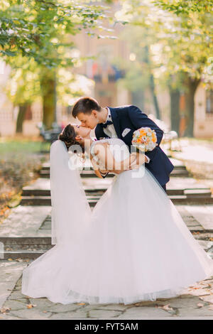 Glückliches Hochzeitspaar charmant Brunet und Bräutigam Braut tanzen im Park auf der Treppe Stockfoto