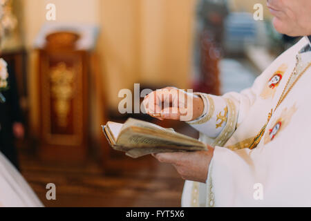 Priester setzt den Ring am Finger der Braut während der Trauung Stockfoto