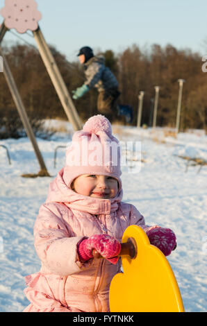 Kinder schwingen auf einer Schaukel im winter Stockfoto