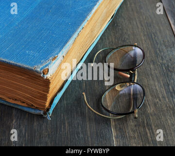 Retro-Brille und altes Buch auf einem hölzernen Hintergrund Stockfoto