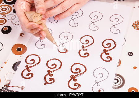 Hände auf Dessert Konditor macht Schokolade Schriftrollen oder Wirbel für Kuchendekoration Stockfoto