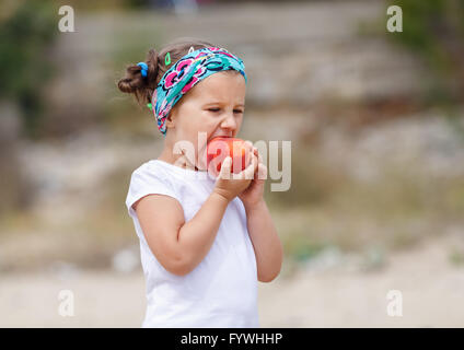 Babymädchen isst einen Pfirsich Stockfoto