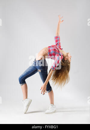 Junge moderne tanzende Mädchen in Jeans auf grau Stockfoto
