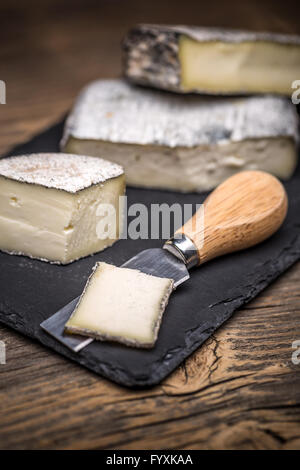 Weichkäse-Stücke auf schwarzem Schiefer Stockfoto
