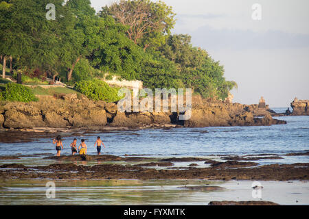 Kinder spielen auf den Felsen am südlichen Ende der Bucht von Jimbaran, Bali. Stockfoto