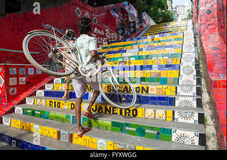 RIO DE JANEIRO - 29. März 2016: Ein Radfahrer geht sein Fahrrad, das bunte Mosaik-Fliesen an den Selaron-Stufen. Stockfoto