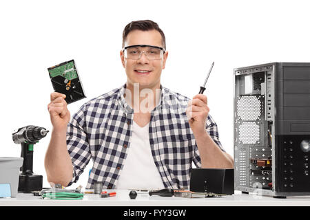 Männliche PC-Techniker hält ein Computerteil und einem Schraubenzieher isoliert auf weißem Hintergrund Stockfoto