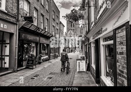 Fußgänger schiebt sein Fahrrad von einem gepflasterten Seitenstraße in Richtung Hereford Kathedrale. Stockfoto