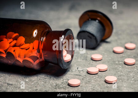 Glasflasche mit Pillen verschüttet auf steinernen Tisch in Nahaufnahme. Konzept der Behandlung, sucht, Medizin und Gesundheitswesen. Stockfoto