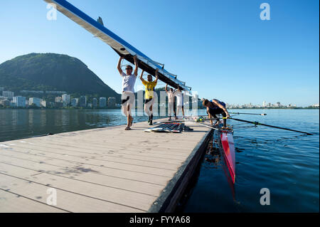 RIO DE JANEIRO - 22. März 2016: Brasilianische Ruderer tragen ihr Boot zurück zum Clubhaus am Lagoa Rodrigo de Freitas-Lagune. Stockfoto