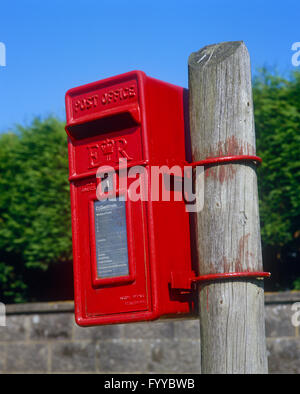 Roten Briefkasten auf einem Holzstab außerhalb. Stockfoto