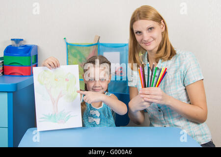 Fünf-Jahres-Girl zeigt auf das Bild, meine Mutter hält in den Händen der Buntstifte Stockfoto