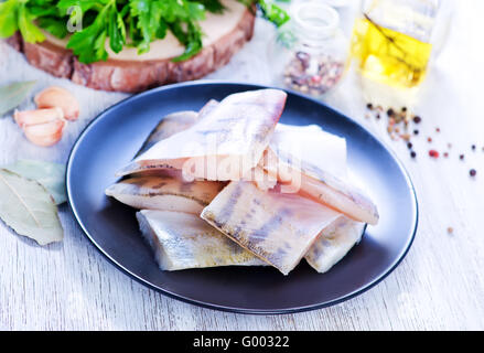 roher Fisch-Filet auf Teller und auf einem Tisch Stockfoto