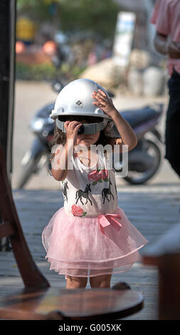 Lustige Kinder. Amüsantes Bild eines Kindes, das mit einem harten Hut zu kämpfen hat. Stockfoto