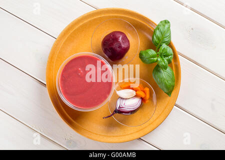 Rote Beete Creme Suppe mit Stücken von Rüben und Zwiebeln auf braune Keramik-Platte Stockfoto