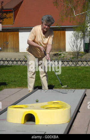 Seniorensport /Elderly Dame auf einem Mini-Golfplatz Stockfoto