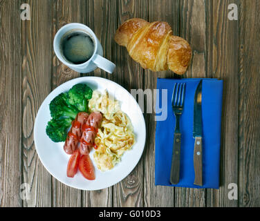 Land-Frühstück - Rührei, Würstchen, Gemüse, Kaffee und croissant Stockfoto